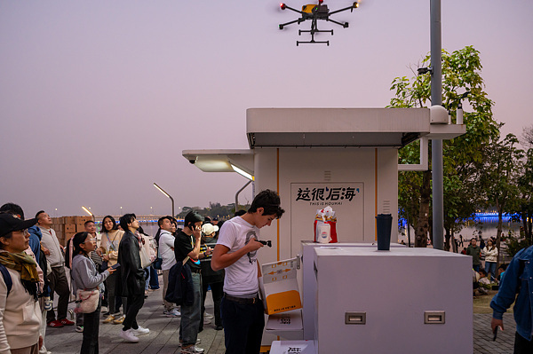 在深圳,外國游客體驗(yàn)無人機(jī)外賣送餐。