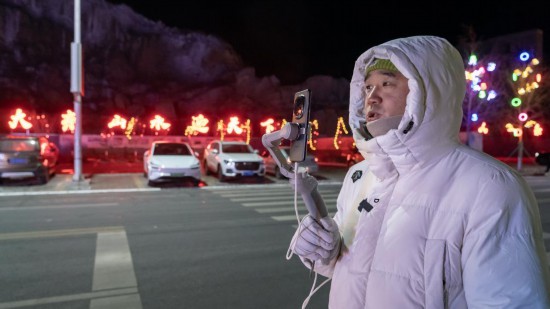 在吉林市阿什哈達霧凇觀景帶，霧凇播報員正在直播。新華社記者 李典 攝