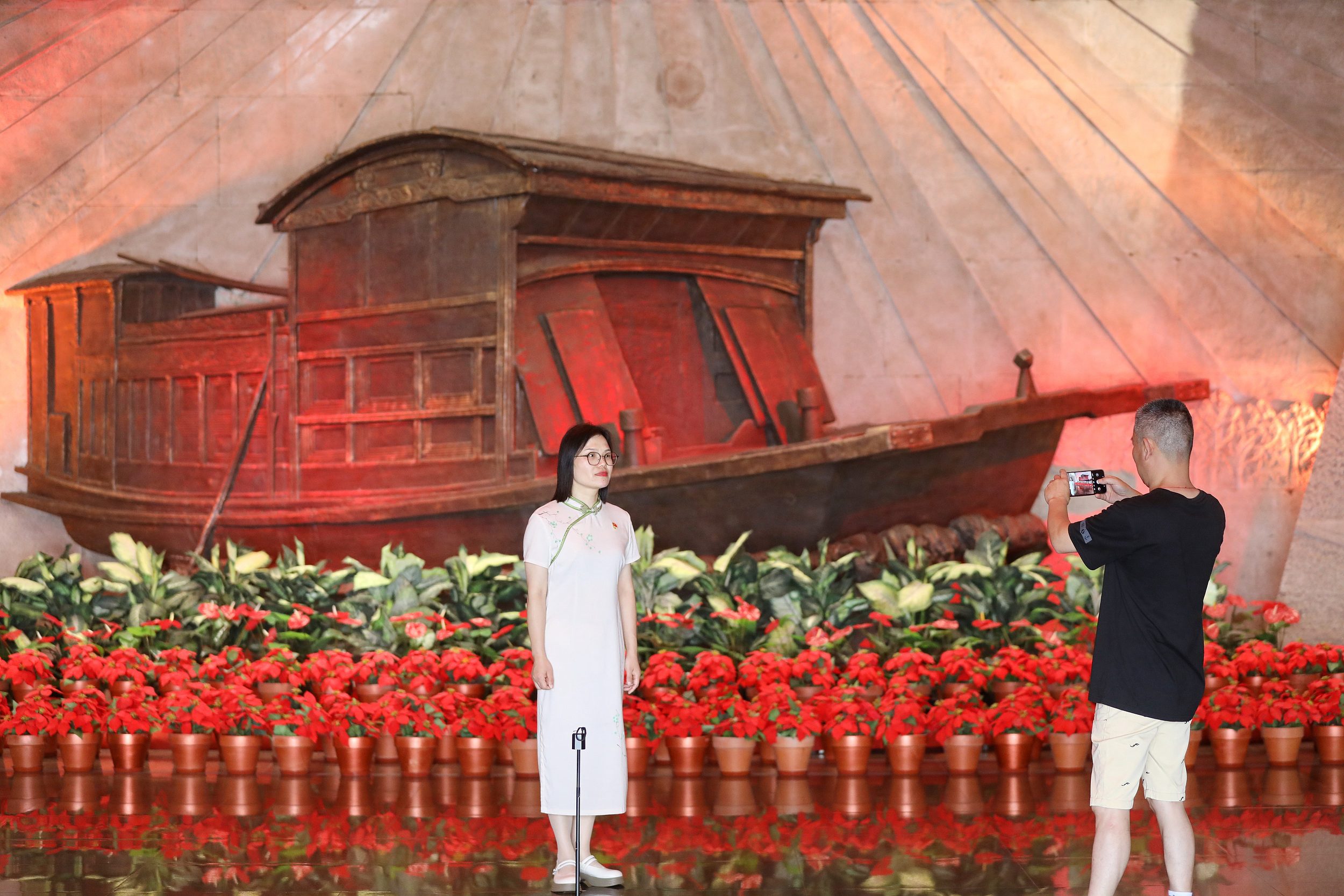 2025年6月24日，浙江嘉興，游客在南湖革命紀(jì)念館與紅船雕塑合影。（圖片來源：視覺中國）