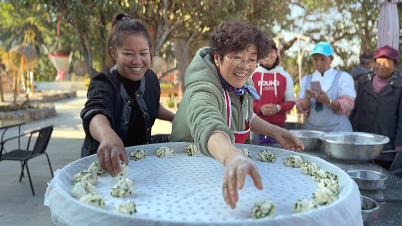 【2】旅居者趙發(fā)英（圖左二）教曼海村村民做花卷。陶思源-攝
